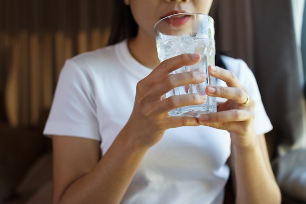 Close up of female drinking from a glass of water. Health care concept