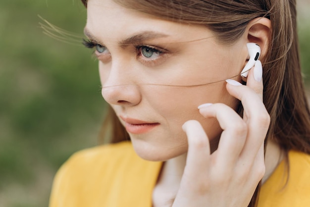 Close up of female ear with wireless earphone inside listening to music young beautiful woman with w