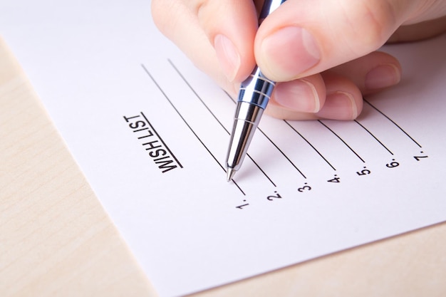 Close up of female hand writing her wish list with pen