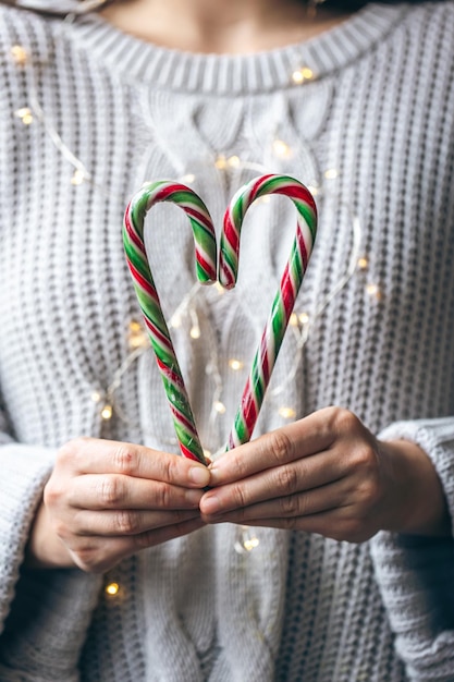 Close up of female hands holding candy canes in the form of heart