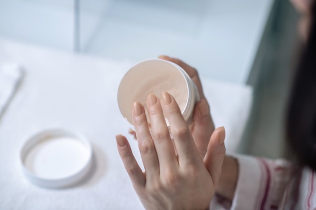 Close up of female hands holding a jar of hand cream