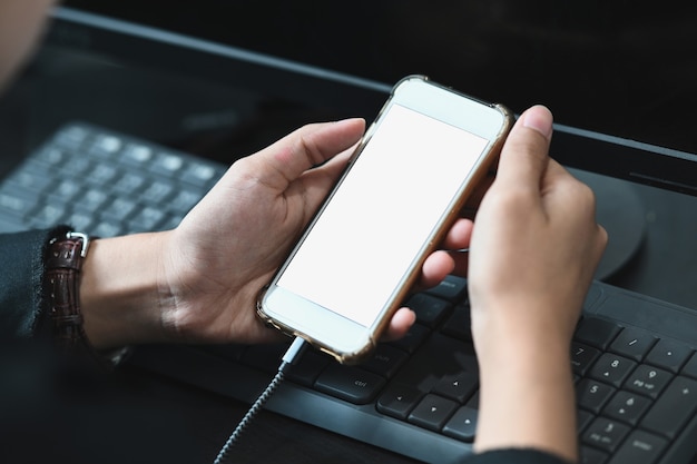 Close up on female hands holding smartphone with blank screen on her workspace