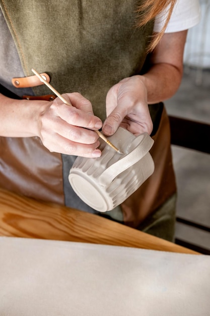 Close up female hands make dishes from clay Woman potter in apron making pottery in studio