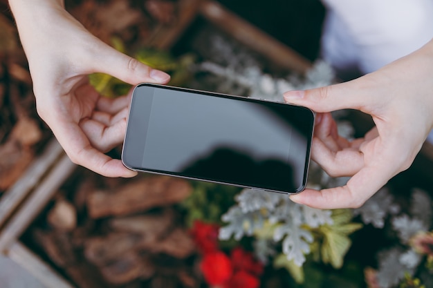 Close up female hands take picture on mobile phone with blank empty screen