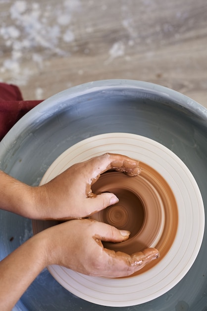 Close-up female hands twist ceramic utensils on a potter's wheel top view