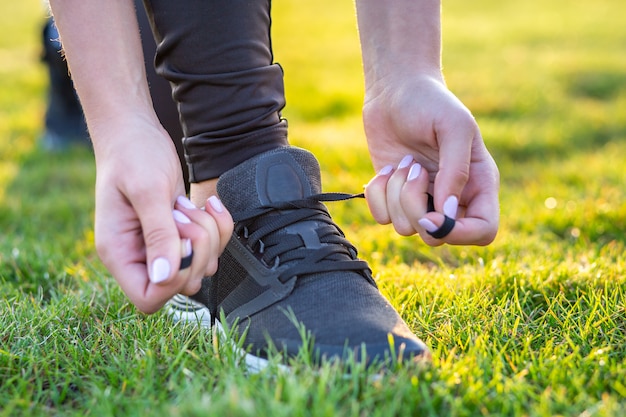 Close-up of female hands tying shoelace on running shoes before practice. Runner getting ready for training. Sport active lifestyle concept.