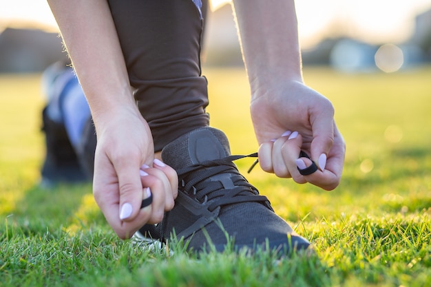 Close-up of female hands tying shoelace on running shoes before practice. Runner getting ready for training. Sport active lifestyle .