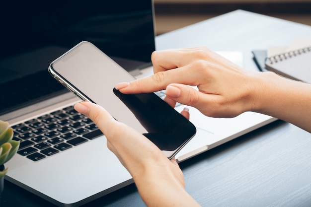 Close up of female hands using smartphone at office table