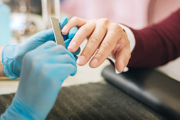 Close up of female hands wearing gloves and applying file