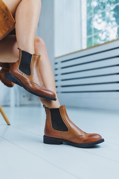 Close up of female legs in brown leather Chelsea boots New autumn collection of women's leather shoes 2022