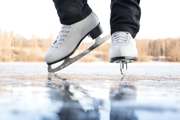 Close up of female legs in white ice skate boots on outdoor ice rink