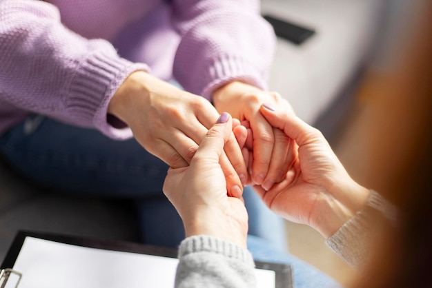 Close up of a female psychologist holding woman's hands during a therapy session Psychotherapist supporting her depressed patient