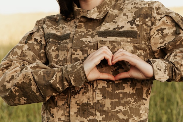 Close up female soldier showing heart love shape sign on velcro patch military uniform