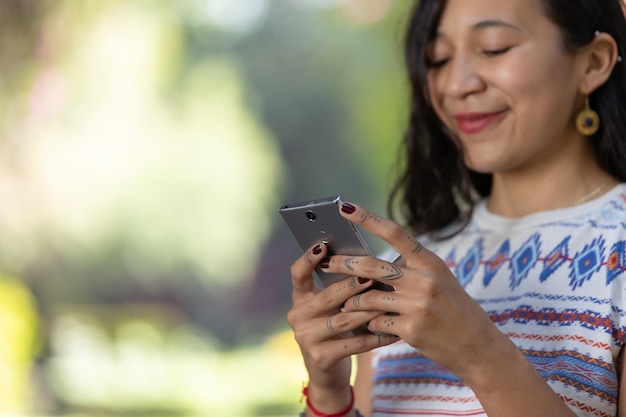 Close up of female tattooed hands using smartphone