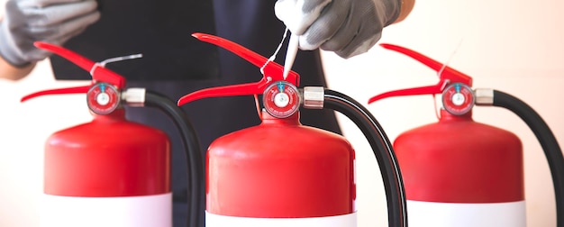 Close up fire extinguisher and firefighter checking pressure gauge level