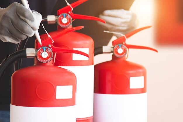 Close up fire extinguisher and firefighter checking pressure gauge level