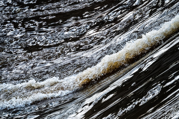 Close up of flowing water rapid water splashes of an white water river or stream bubbly water