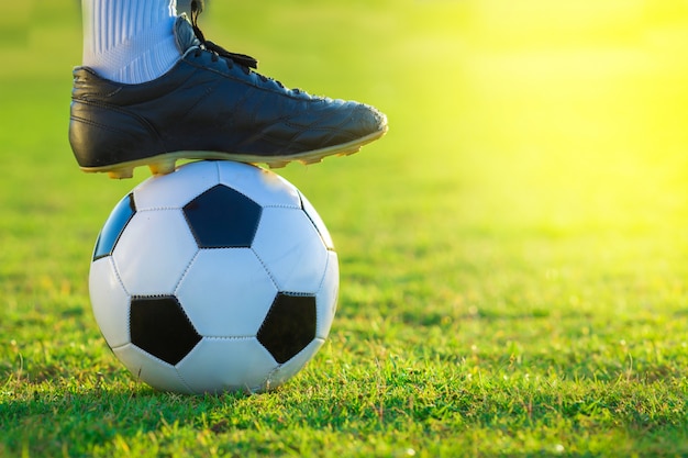 close up of football player tread on the ball on green field