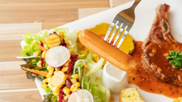 Close up of a fork impaled on a sausage.