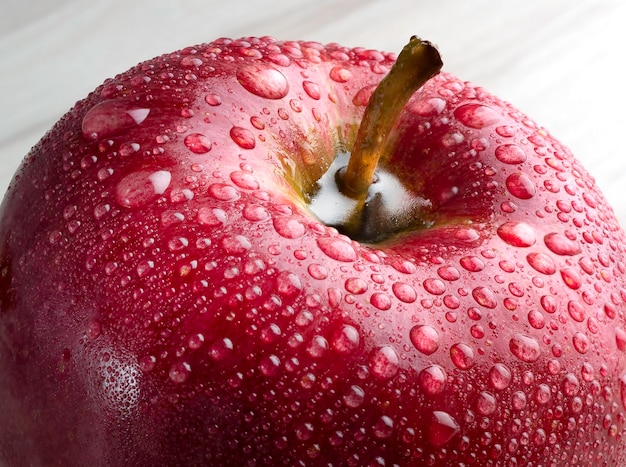 A close up fragment of a red apple with water drops on a gray background