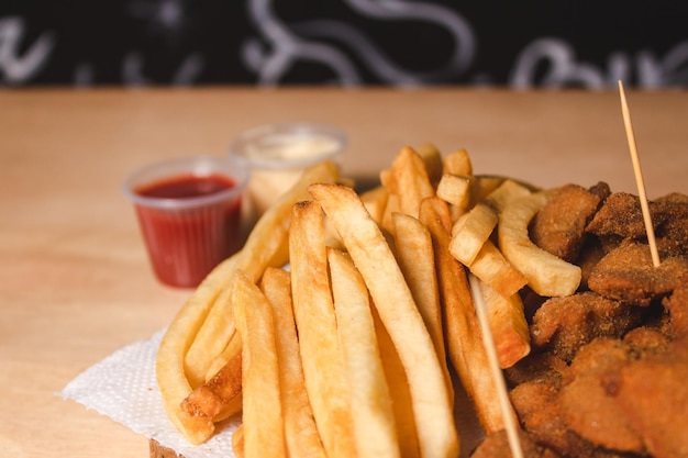 Close-up of French fries with toppings on a wooden board.