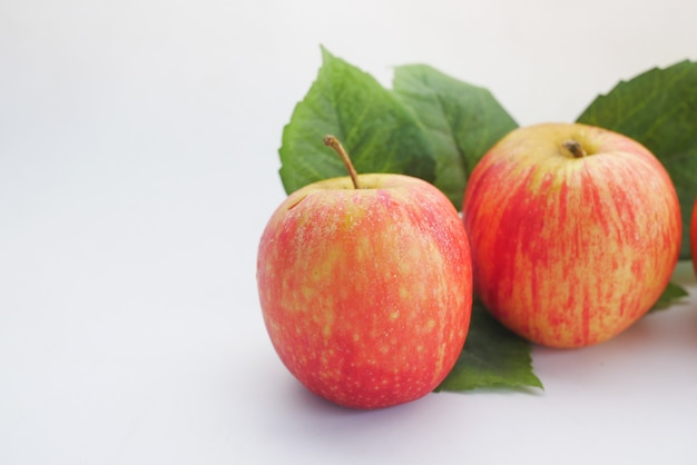 Close up of fresh apple with leaf on white surface