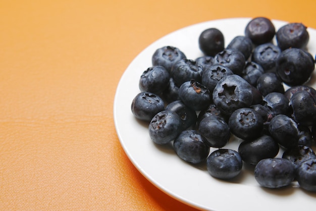 Close up of fresh blue berry on a plate on orange background