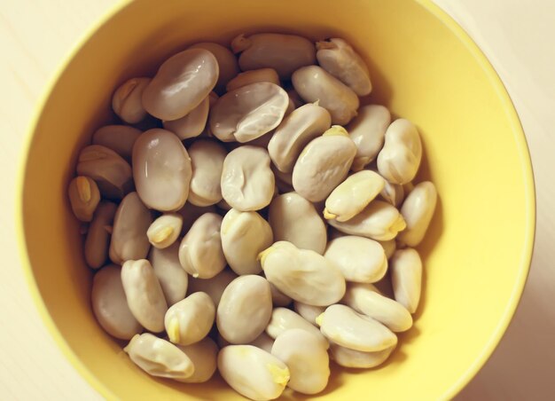 A close up of fresh broad beans in a yellow cup