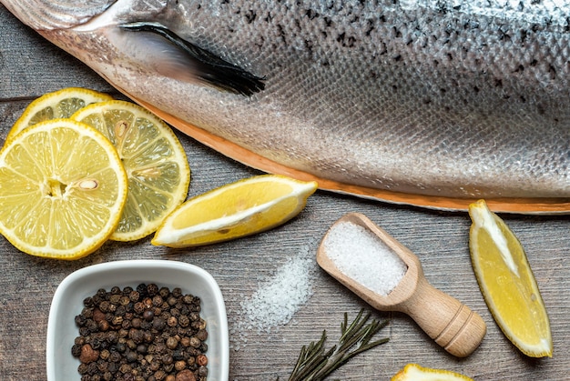 Close up Fresh raw salmon red fish with spices salt lemon pepper rosemary on dark wooden background salmon cooking Sea fish healthy food top view