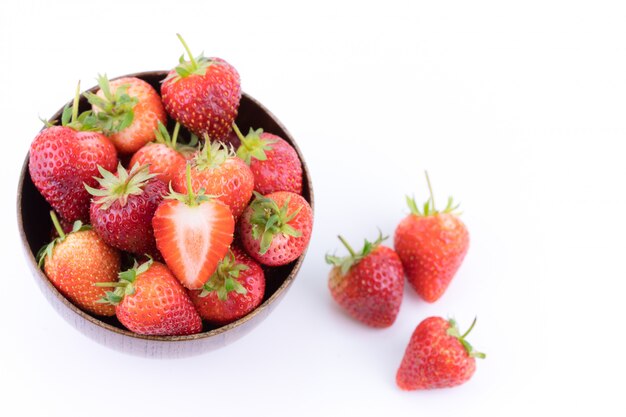 Close up fresh strawberries fruits in a wooden bowl isolated on white background