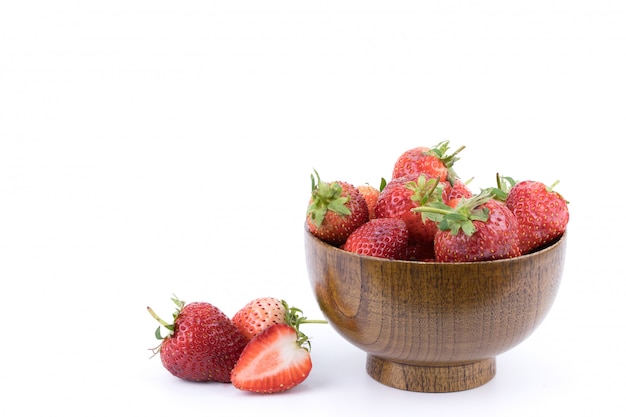 Close up fresh strawberries fruits in a wooden bowl isolated on white background.