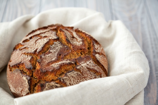 Close-up freshly baked hot rye circle bread in a linen cloth