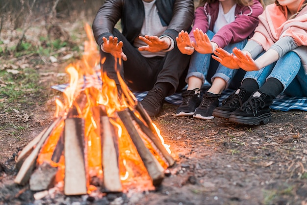 Close-up friends warming at fire camp