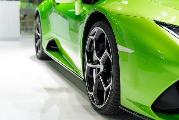 Close up front of new green car with Magnesium alloy wheel parking on car showroom.