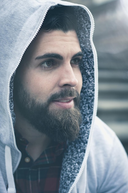 Close up on full beard young man with grey hoodie on head Hip hop rapper style Hipster male model