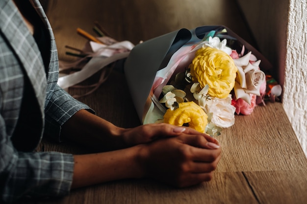 Close-up of a girl's hands in a cafe with a bouquet lying next to it.Beckett is lying on the counter in the cafe and next to the girl's hands.