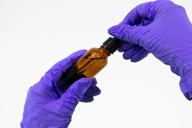 Close up glass cosmetic jar in hands with rubber gloves on white backgroung