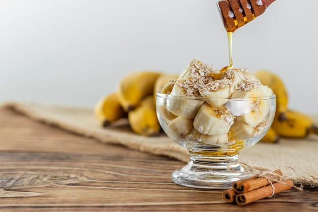 Close up on glass jar with pieces of banana with oats and honey