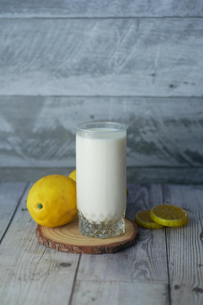 Close up of glass of milk and lemon on table