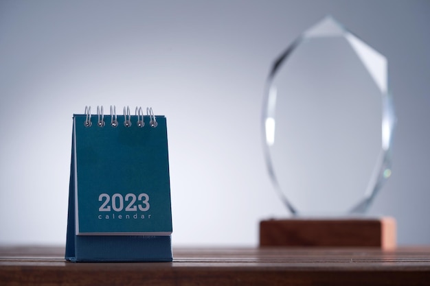 Close up of a glass trophy and desk calendar 2023