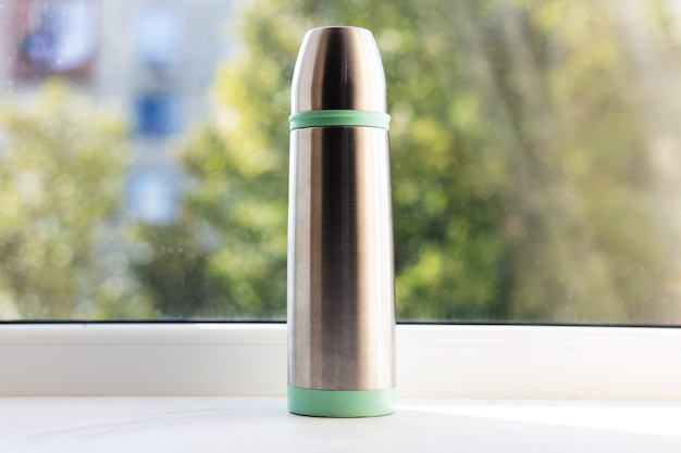 Close-up of glossy with green thermos.