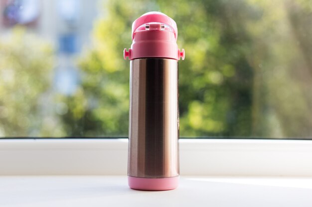 Close-up of glossy with pink thermos.