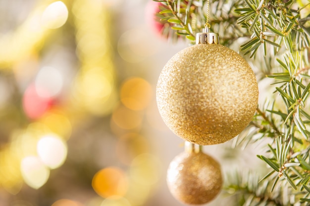 Close-up of gold Christmas ball hanging on Christmas tree.