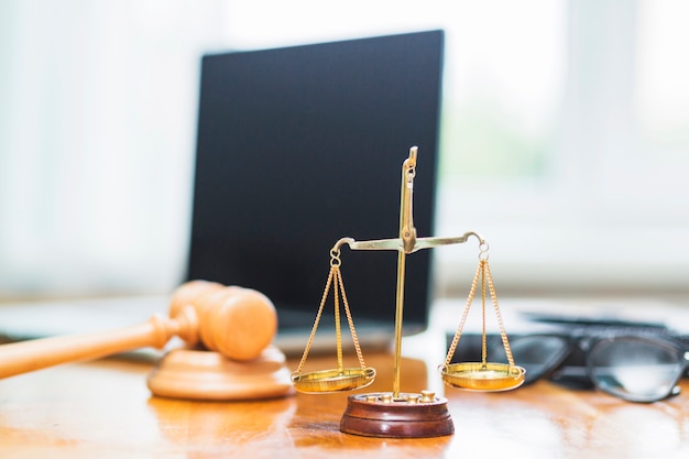 Close-up of golden justice scale on wooden desk in courtroom