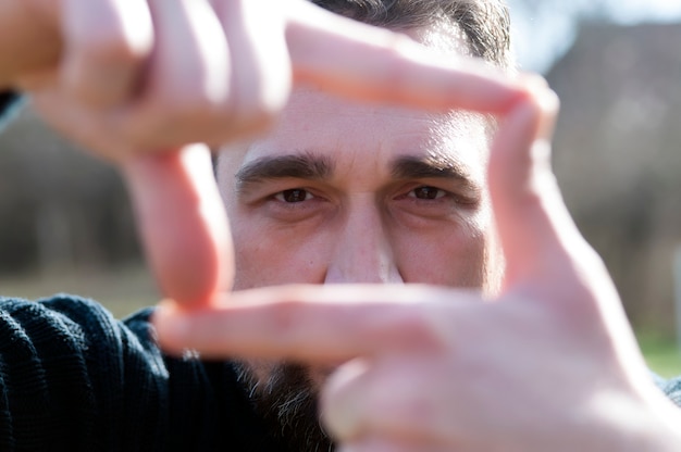 Photo close up gorgeous businessman, looking at the camera while making a hand frame gesture.