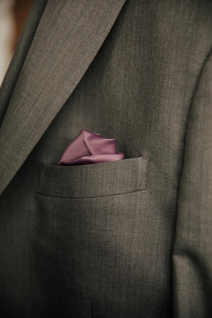 Photo close up of gray mans dress suit pocket with purple pockt square