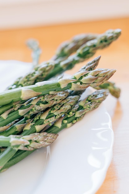 Close up green asparagus on white plate and wooden background Macro shot