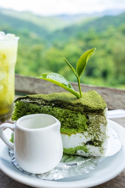 Close up Green tea cake on white disk with matcha green tea on the black wooden