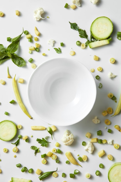 Close up of green vegetables and fruits on the plate for white table. Healthy eating and food for vegans