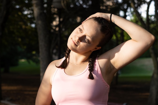 Close up of greeneyed woman stretching her neck outdoors with unfocused background